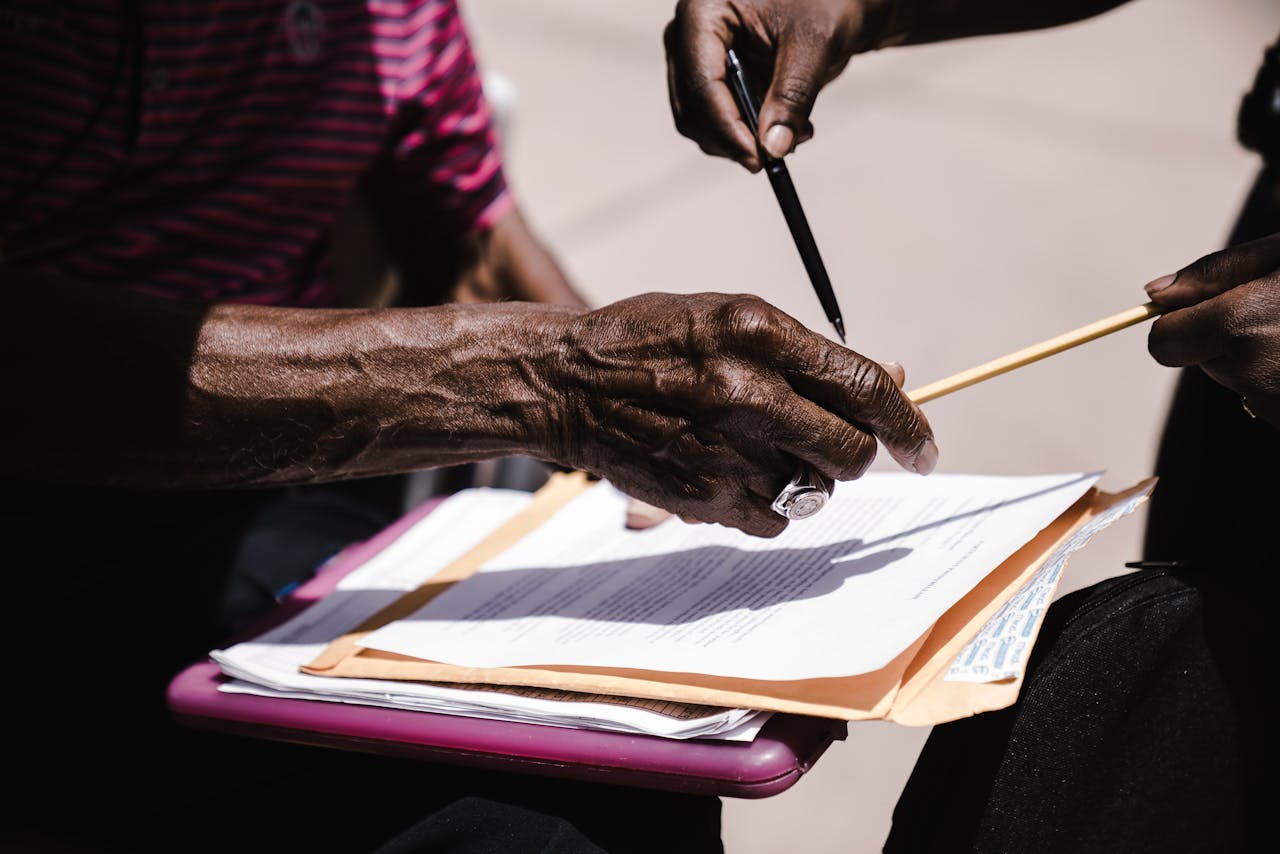 Close-up of hands exchanging documents with pens outdoors. Business agreement concept.